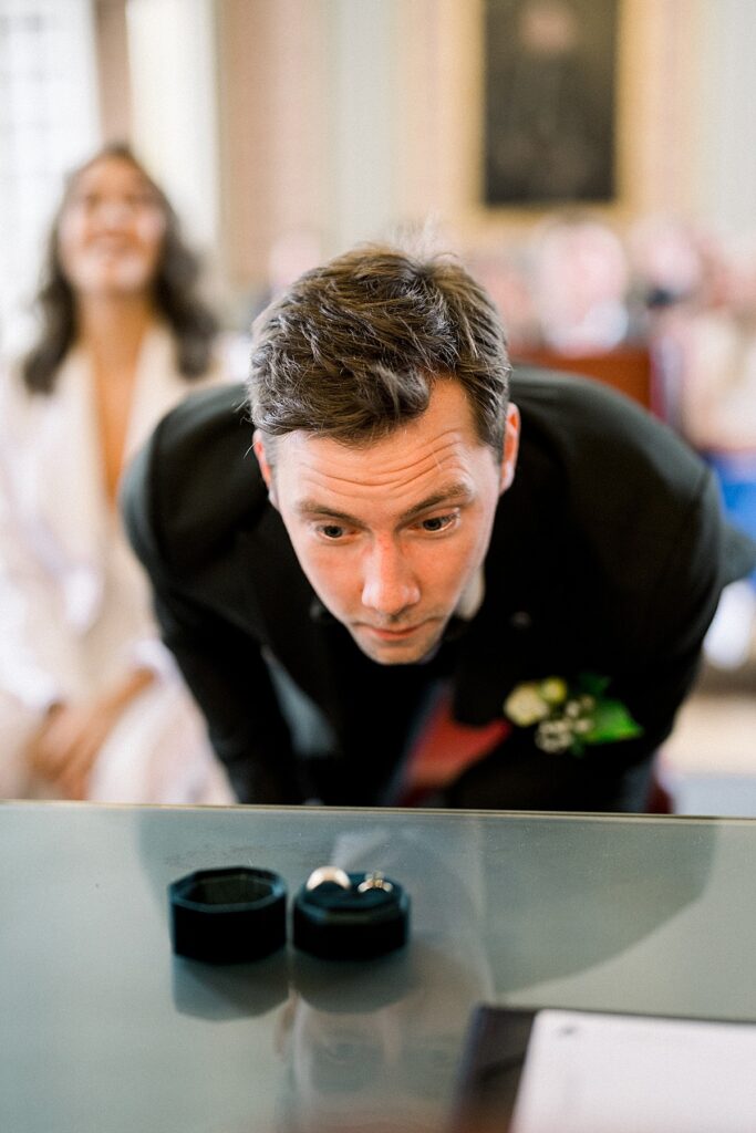 groom looking at the rings