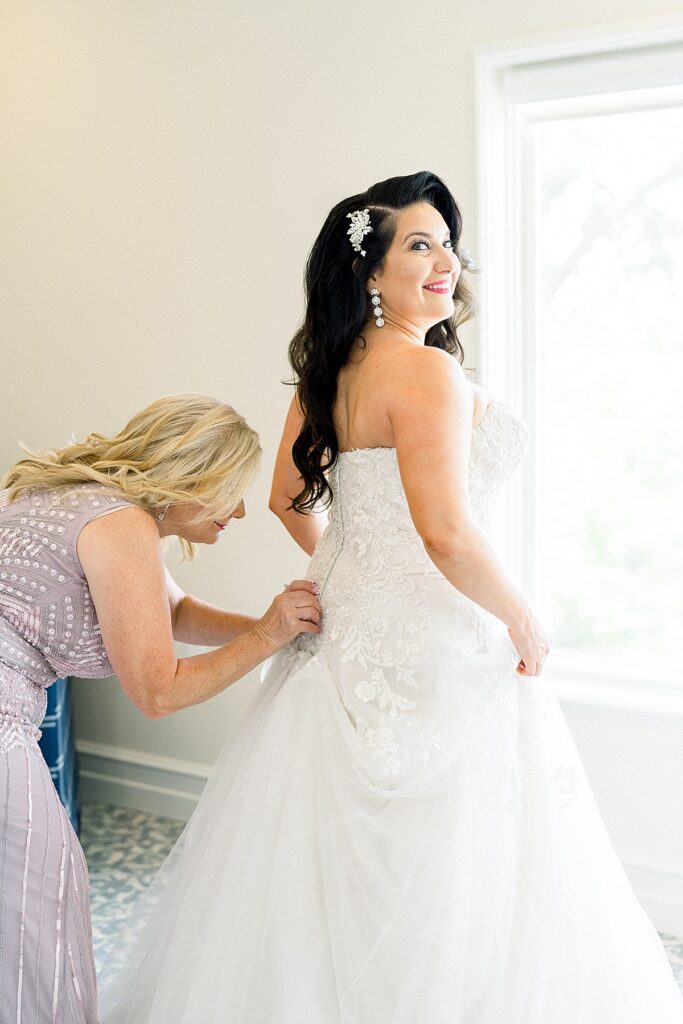 mom helping bride with her dress